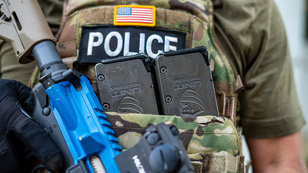 Deux chargeurs UNIT4 UNIT Solutions sur gilet tactique police — opérateur avec fusil d'entraînement bleu